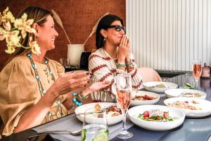 Duas mulheres sentadas à mesa a comer comida. em The Marblous Athens em Atenas