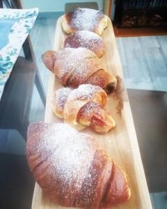 quatro produtos de pastelaria numa tábua de cortar madeira com açúcar em pó em Casa Escape em Terrasini
