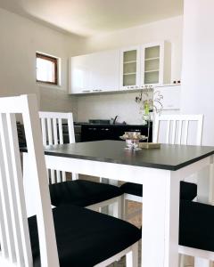 een keuken met een eettafel en witte kasten bij Blue Sky Apartments in Slatine