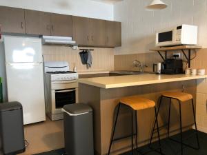 a kitchen with a refrigerator and a counter with stools at Alpine Cabin- Spa/Pool/Sauna in Mount Hotham