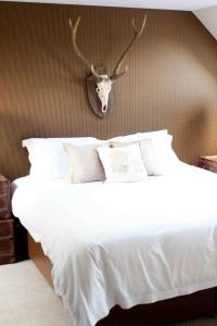 a bedroom with a white bed with antlers on the wall at Hideaway Lodge in Kingussie