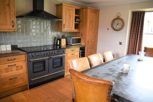cocina con fogones y mesa con sillas en Hideaway Lodge, en Kingussie