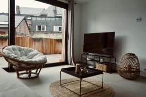 een woonkamer met een televisie en een stoel bij La Terrasse - Résidence Le Cercle in Marche-en-Famenne