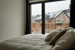 a bed in a bedroom with a large window at La Terrasse - Résidence Le Cercle in Marche-en-Famenne