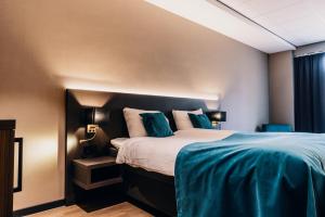 una camera da letto con un grande letto con cuscini blu di Hotel Hoogeveen a Hoogeveen