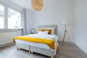- une chambre blanche avec un grand lit et une couverture jaune dans l'établissement Ferienwohnung res publica, à Wuppertal