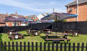 a group of picnic tables with umbrellas on the grass at The Old Castle Hotel in Rodwell