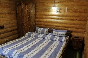 1 dormitorio con 1 cama en una cabaña de madera en "Лісова Ягода" en Yablunytsya