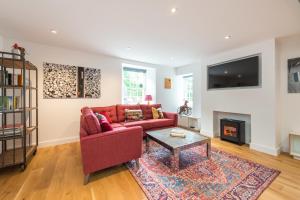 ein Wohnzimmer mit einem roten Sofa und einem Kamin in der Unterkunft Charming 3 Bed Village Green Cottage East Lothian in Gifford