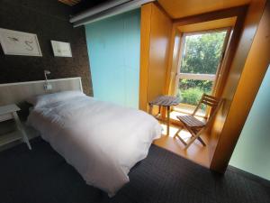 1 dormitorio con cama, ventana y silla en Urdaibai Bird Center, en Gautegiz Arteaga