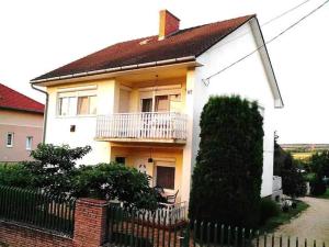 una casa blanca con una valla delante en Privát, saját fürdős, erkélyes szoba a Balatonon, en Kőröshegy