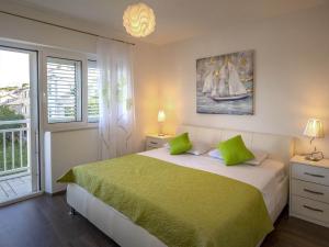 sypialnia z łóżkiem z zieloną pościelą i oknem w obiekcie Apartments Snjezana w mieście Povlja