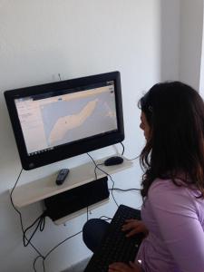 uma mulher sentada em frente a um monitor de computador em Hotel Maria-Elena em Agios Kirykos