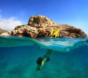 カンブリルスにあるCasa bonmont con vistas al mar piscina y port aventuraの海の岩の近くで泳ぐ者