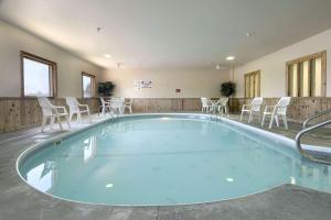 uma grande piscina com cadeiras e mesas brancas em Super 8 by Wyndham Mason City em Mason City