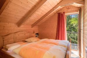 uma cama num quarto de madeira com uma janela em Haus der Sinne Bregenzerwald em Tannen