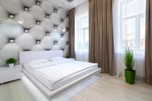 a bedroom with a large white bed with a padded wall at LEOGRAND VIP Apartments on Pidhirna 3 in Lviv