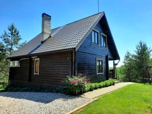 a small black house with flowers in front of it at Sodyba Vilagio in Alanta