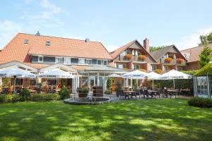 una casa grande con un patio con mesas y sombrillas en Flairhotel Hubertus, en Bad Zwischenahn