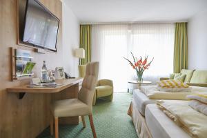 Habitación de hotel con cama y escritorio con TV. en Flairhotel Hubertus, en Bad Zwischenahn