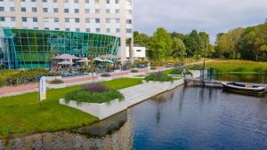 a building next to a river with a boat in it at Flonk Hotel Groningen Zuid, BW Signature Collection in Groningen