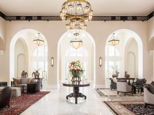 a lobby with arched windows and a chandelier at Raffles Hotel Le Royal in Phnom Penh