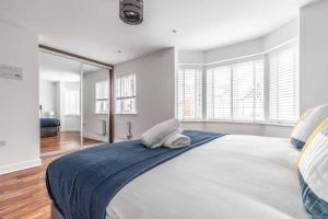 een witte slaapkamer met een groot bed met blauwe lakens bij STYLISH 4 BED/2 BATH & PARKING - PINEWOOD/HEATHROW in Slough