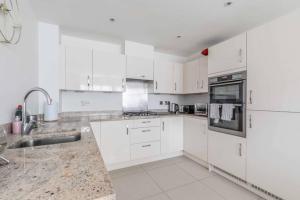 uma cozinha branca com armários e electrodomésticos brancos em STYLISH 4 BED/2 BATH & PARKING - PINEWOOD/HEATHROW em Slough
