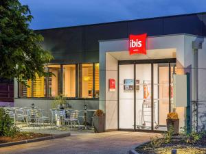 un restaurant avec des tables et des chaises en face d'un bâtiment dans l'établissement ibis Rennes Cesson, à Cesson-Sévigné