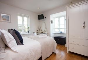 a bedroom with a white bed and two windows at 8 Fernhill in Carbis Bay