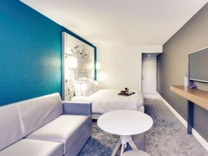 a hotel room with a couch and a bed at Hôtel Mercure Paris Centre Gare Montparnasse in Paris