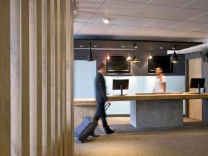 a man with a suitcase walking past a counter at ibis Bordeaux Centre - Gare Saint-Jean in Bordeaux