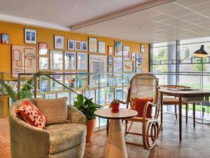 une chambre avec un canapé, des tables et un mur de photos dans l'établissement Novotel Suites Nice Airport, à Nice