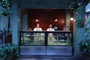 deux personnes se tenant derrière un comptoir avec de la nourriture dans l'établissement The Elgin Fairlawn, Kolkata, à Kolkata