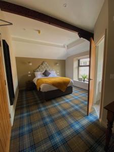 a bedroom with a bed with a yellow blanket on it at The Lounge Hotel & Bar in Penrith