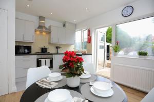 a kitchen and dining room with a table with red flowers at Aisiki Stays Apartments at Hillingdon, 3-Bedroom & 2-Bathroom, Pet-Friendly House with Garden, King or Twin Beds with Free Wi-Fi & Parking Space in Hillingdon