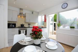 a kitchen and dining room with a table with red flowers at FW Haute Apartments at Hillingdon, 3 Bedrooms and 2 Bathrooms Pet Friendly HOUSE with Garden, with King or Twin beds with FREE WIFI and FREE PARKING in Hillingdon