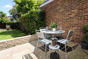 a table and chairs sitting next to a brick wall at FW Haute Apartments at Hillingdon, 3 Bedrooms and 2 Bathrooms Pet Friendly HOUSE with Garden, with King or Twin beds with FREE WIFI and FREE PARKING in Hillingdon