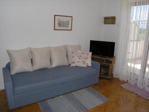 ein blaues Sofa im Wohnzimmer mit TV in der Unterkunft Apartments Jadranka with magnificent views of the sea - Baska in Baška