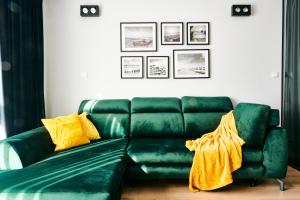 ein grünes Sofa im Wohnzimmer mit gelben Kissen in der Unterkunft EASY RENT Apartments - Diamond in Lublin