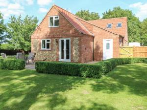 une maison en briques avec une pelouse devant elle dans l'établissement Keepers Cottage, à Beeston