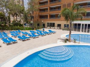 uma piscina com cadeiras azuis e um hotel em Aparthotel BCL Levante Lux em Benidorm