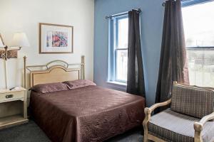 1 dormitorio con 1 cama, 1 silla y 1 ventana en OYO Historic Cameron Hotel Brownsville I-69E, en Brownsville