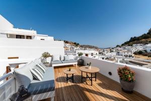 a balcony with tables and chairs on a building at Lindian Polis in Lindos