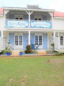 Una casa blanca con un cartel azul. en Sur L'Anse, en Terre-de-Haut