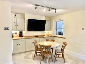 cocina con mesa y sillas y TV en Stunning Estate sleeps 22 private parking & garden, en Hailsham