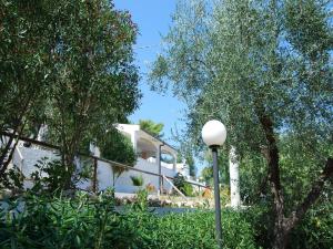 a white house with trees and a street light at Althea Village Residence in Vieste