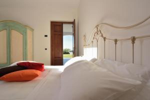 a bedroom with a bed with white sheets and red pillows at AGRITURISMO Masseria Spetterrata in Cisternino