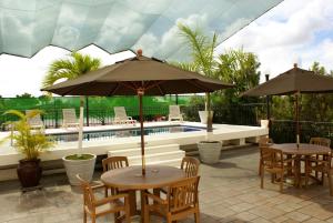 two tables and chairs with umbrellas next to a pool at Hotel San Francisco in Tapachula