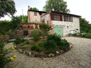 a stone house with a green door in a yard at Tra grilli e cicale in Deruta